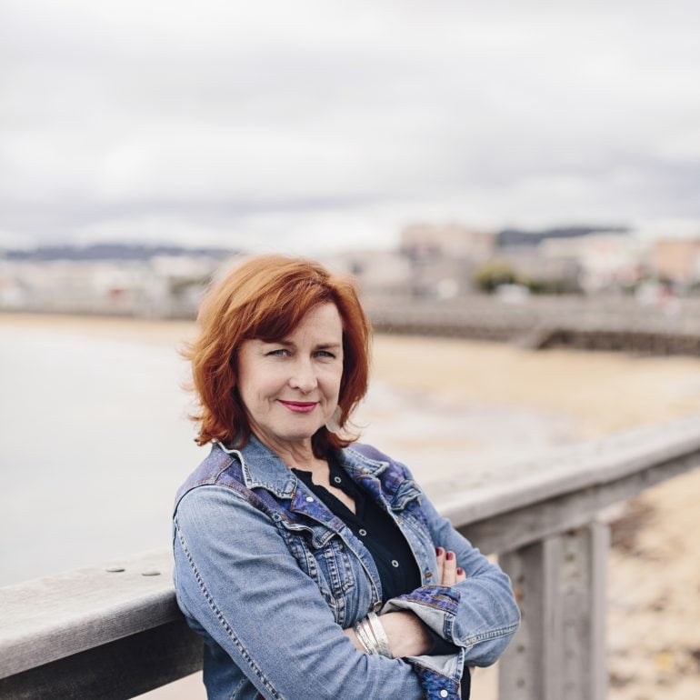 A close up image of Lindy leaning against the Burnie foreshore boardwalk